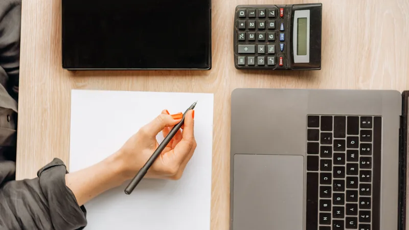 Person working through salary figures on a calculator at a desk with a laptop