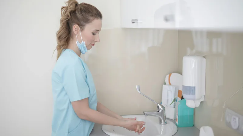Neatly folded nursing scrubs with hospital logo on a washing machine representing deductible laundry and uniform expenses for Australian nurses ATO 2025