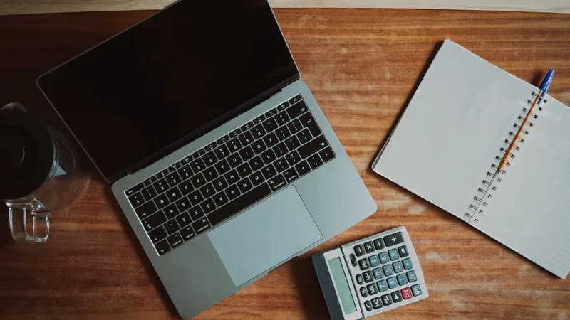 Desk with laptop, calculator and notebook set up to verify superannuation contributions after each payday