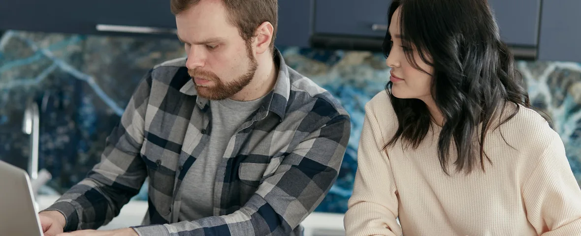 Australian family reviewing budget and bills at dining table with laptop and calculator