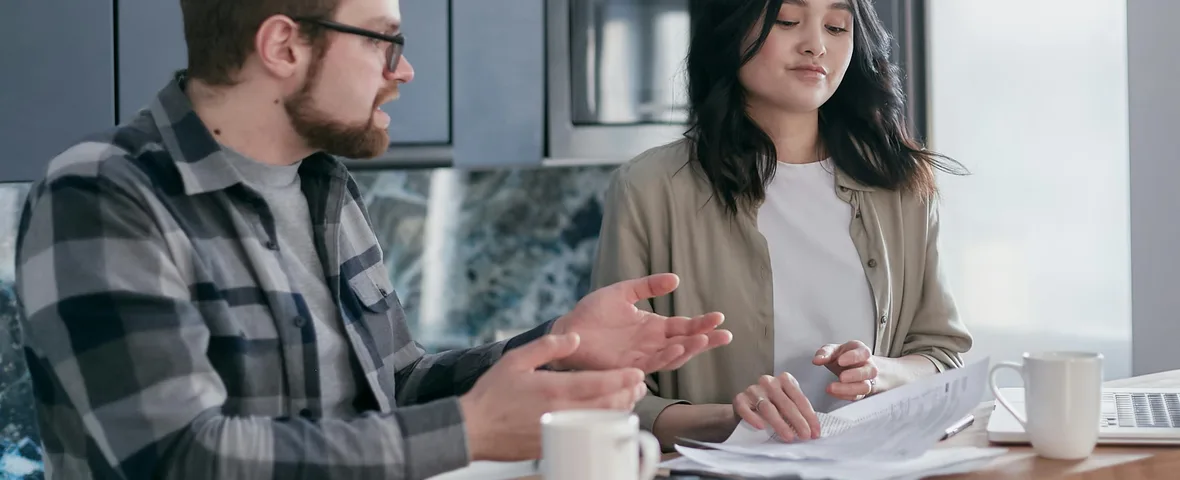 Australian couple reviewing home loan documents on laptop at kitchen table