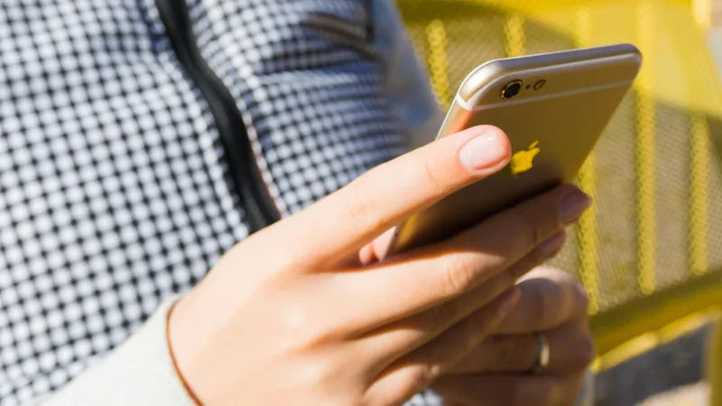 Person checking home loan rate on phone with rising interest rate graph on screen