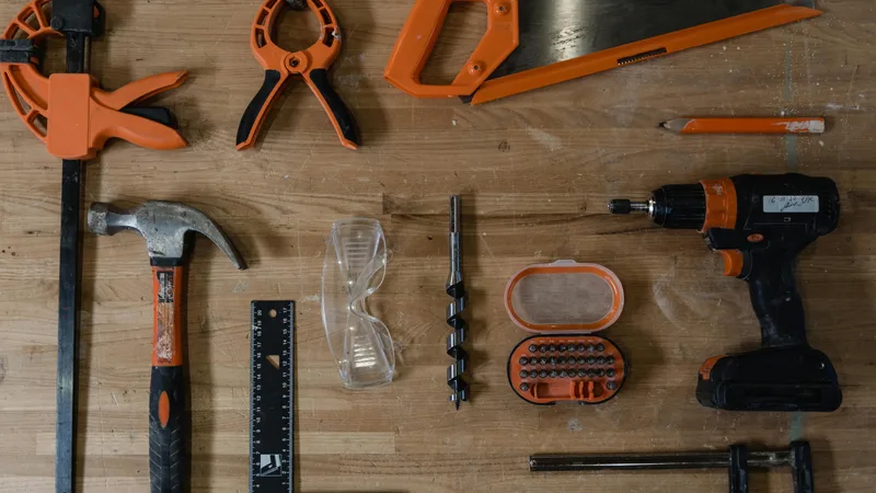 Close-up of tradesperson tools laid out on workbench including multi-tool tape measure drill and safety equipment eligible for ATO tax deduction