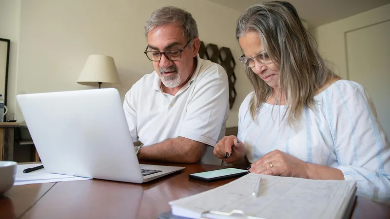 Australian couple reviewing retirement super contributions together at kitchen table with laptop